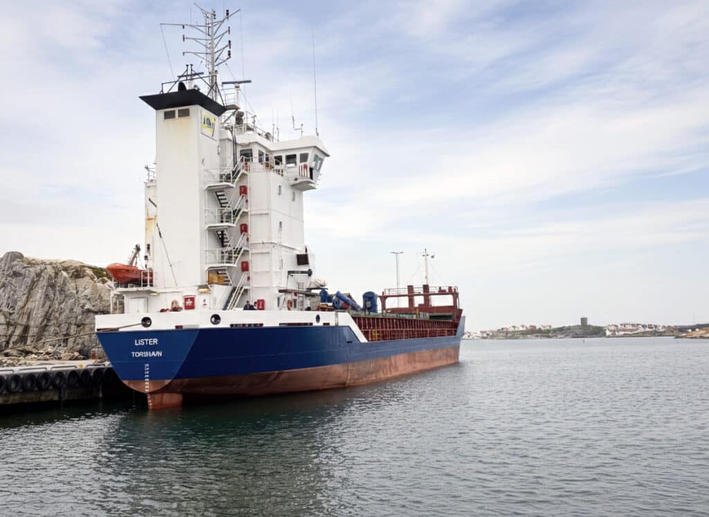 The vessel alongside, seen from the bow with the port of registry on the hull